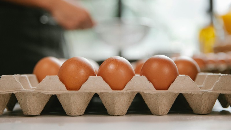Eggs in carton container placed on table near chef cooking food in kitchen, tags: met - pexel