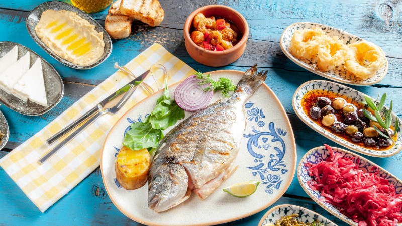 A vibrant Mediterranean meal featuring grilled fish and assorted appetizers on a rustic table., tags: mediterraan voor - pexel